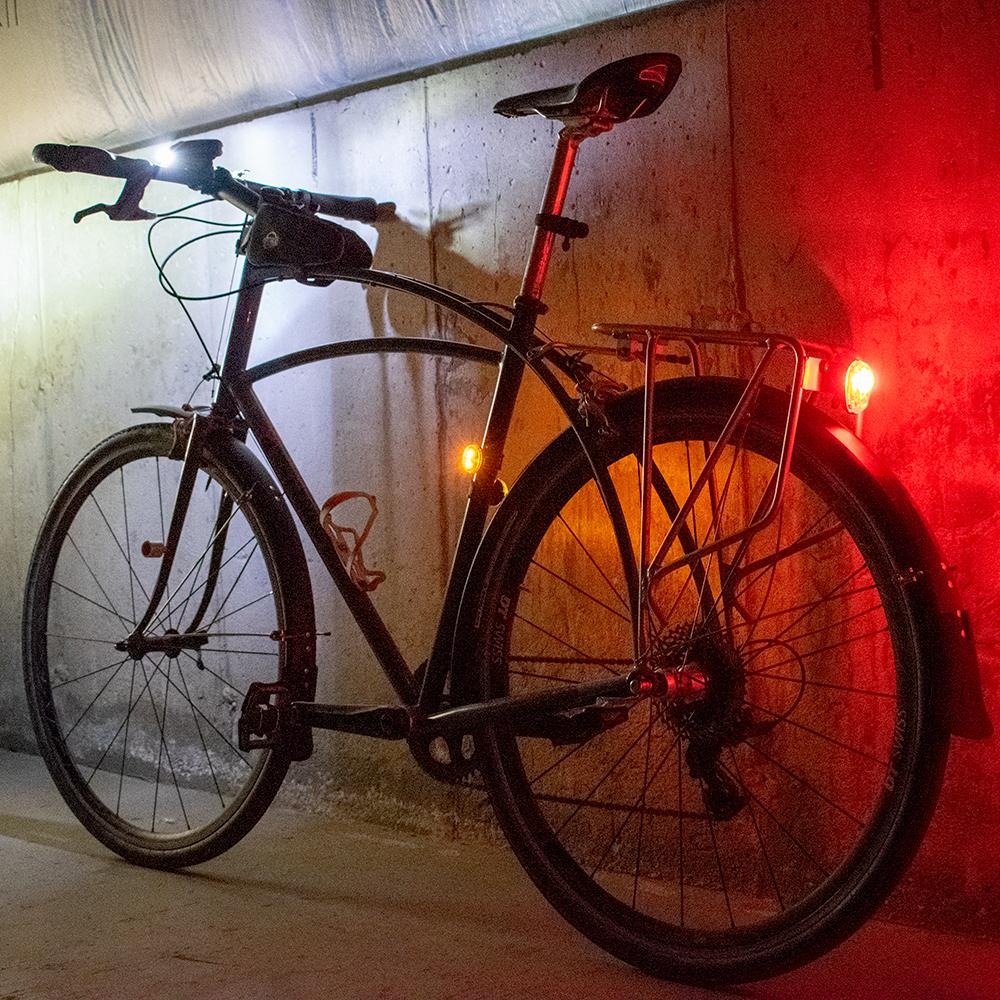 Bicycle stored in a compact home cycling area with helmet and rechargeable bike lights ready for nighttime riding.