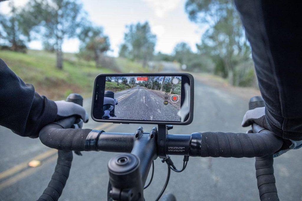 Smartphone mounted securely on bicycle handlebars as part of a cycling recording setup.